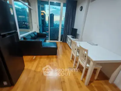 Modern living room with city view, featuring sleek black sofa and dining area with wooden flooring.