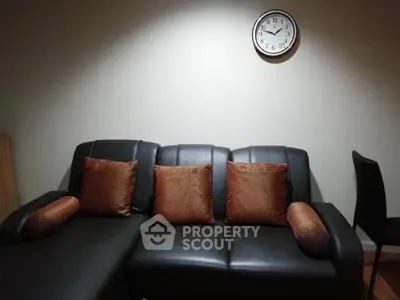 Cozy living room with stylish black leather sofa and wall clock