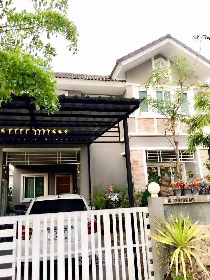 Charming two-story house with carport and lush greenery in a serene neighborhood.
