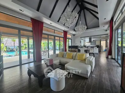 Luxurious open-plan living room with high ceilings and pool view, featuring elegant chandeliers and modern decor.