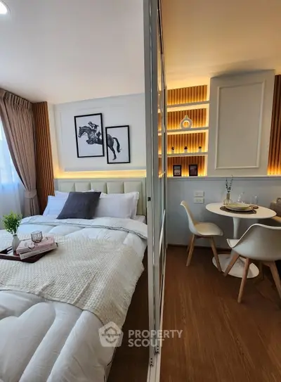 Modern bedroom with cozy dining area, featuring elegant decor and warm lighting.