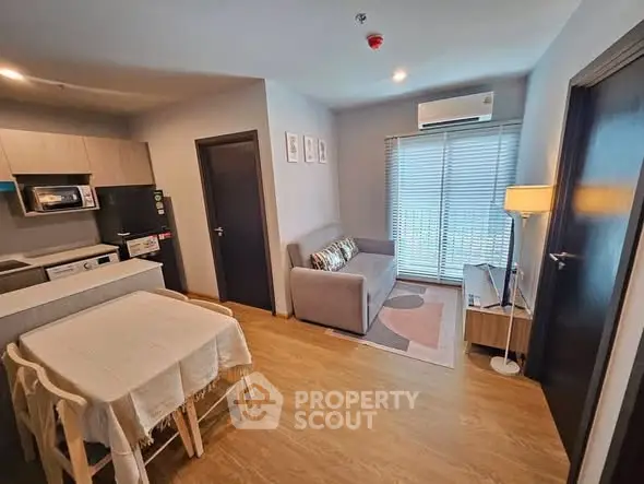 Modern living room with open kitchen, cozy sofa, and dining area in stylish apartment.