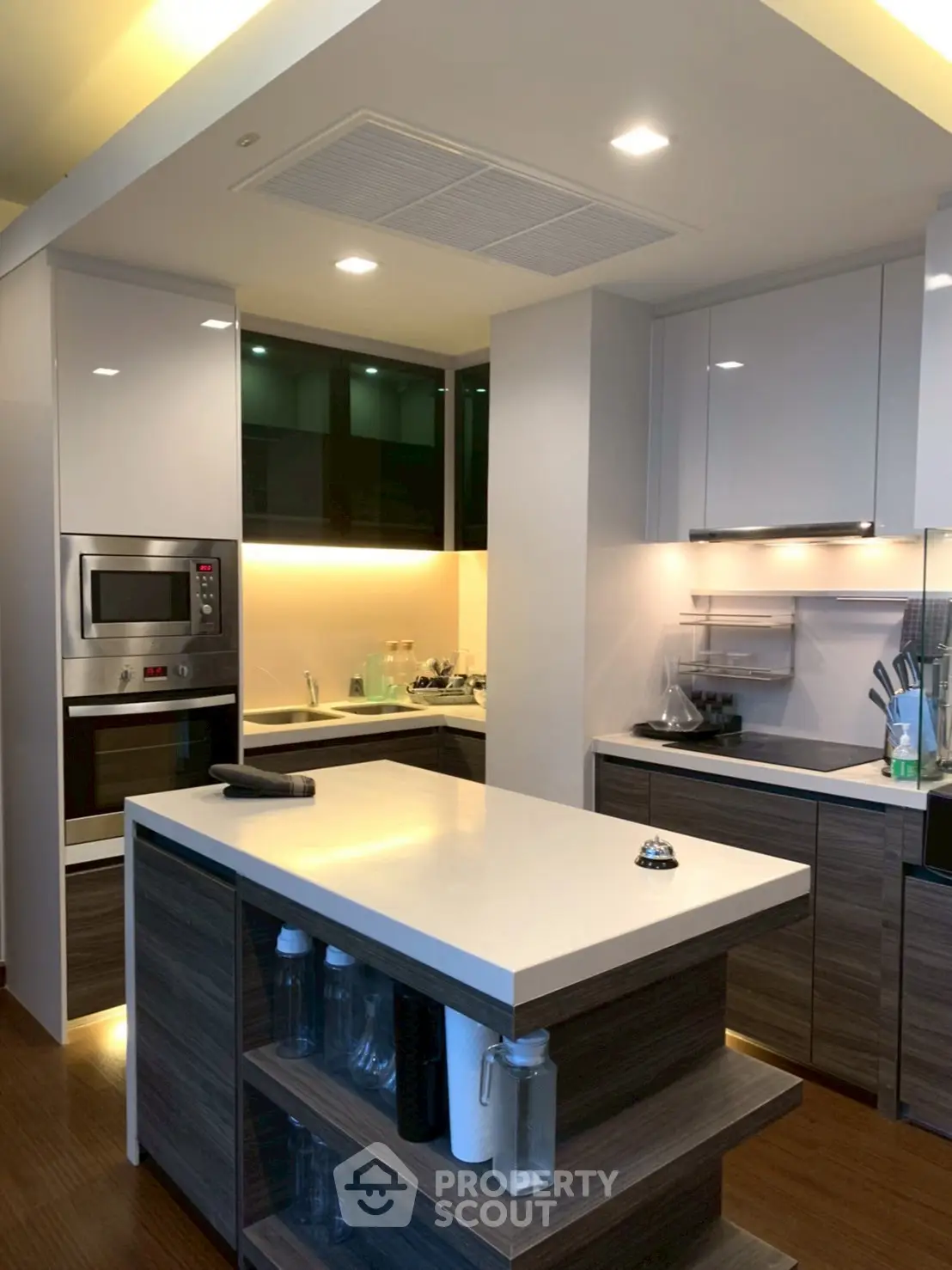 Modern kitchen with sleek design and island, featuring built-in appliances and ambient lighting.