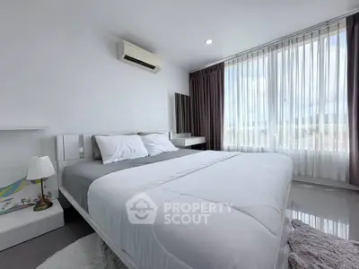 Spacious bedroom with large windows and modern decor, offering abundant natural light and a serene atmosphere.