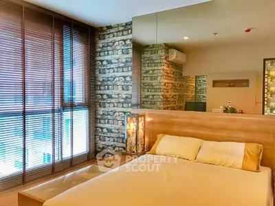 Modern bedroom with stylish brick accent wall and large window with blinds.