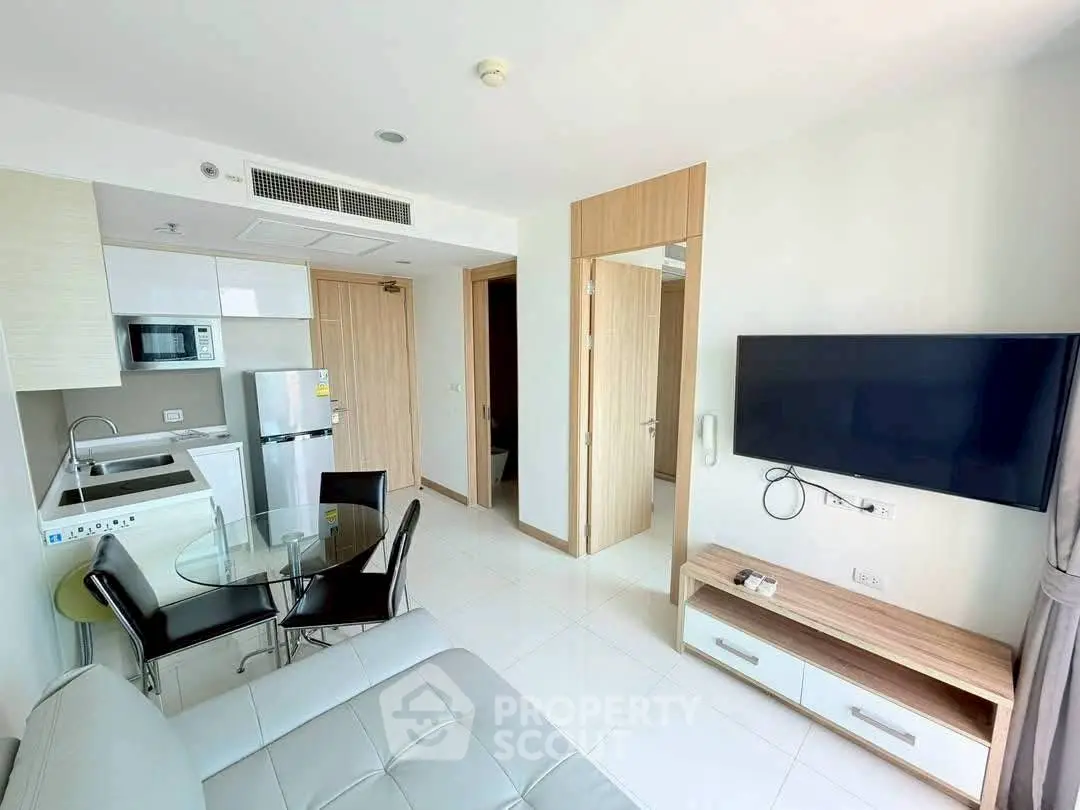 Modern apartment living room with open kitchen, sleek furniture, and wall-mounted TV.