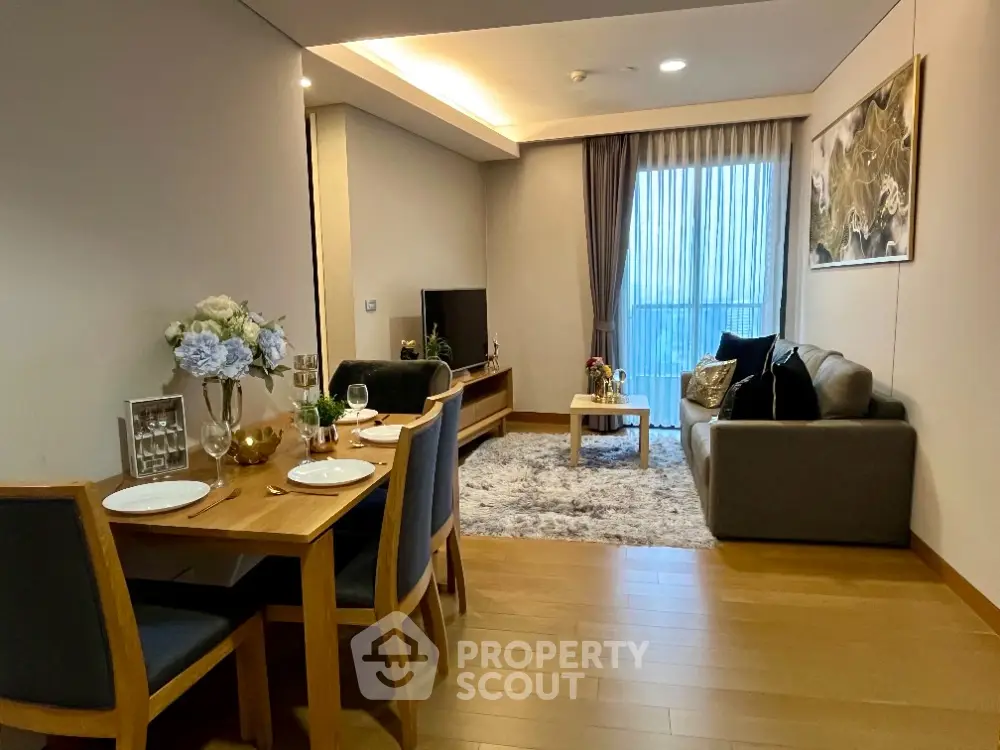 Modern living room with elegant dining area and cozy seating, featuring floor-to-ceiling windows and stylish decor.