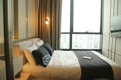 Luxurious bedroom with large window offering stunning city views, elegant decor, and cozy ambiance.