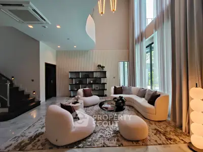 Luxurious modern living room with high ceilings, elegant furniture, and large windows offering natural light.