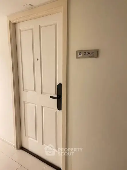 Modern apartment entrance with sleek white door and room number plaque, showcasing secure and stylish living.