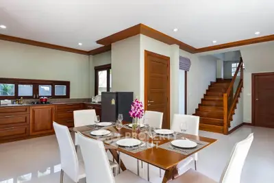 Spacious dining area with elegant wooden staircase and modern kitchen in open layout design.