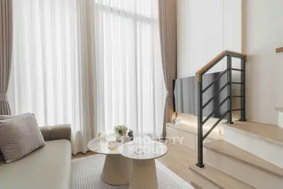 Modern living room with high ceilings, elegant staircase, and stylish decor in a luxury apartment.