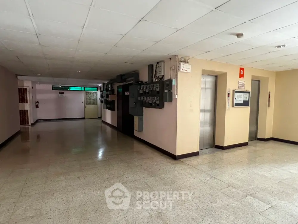 Spacious building corridor with elevator access and utility panels