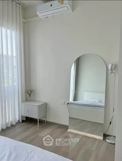 Bright and modern bedroom with large mirror and natural light, perfect for relaxation.