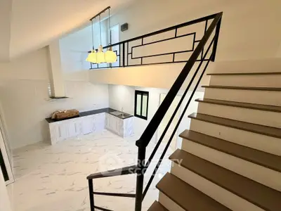 Spacious modern kitchen with open layout and stylish staircase in a bright, airy home.