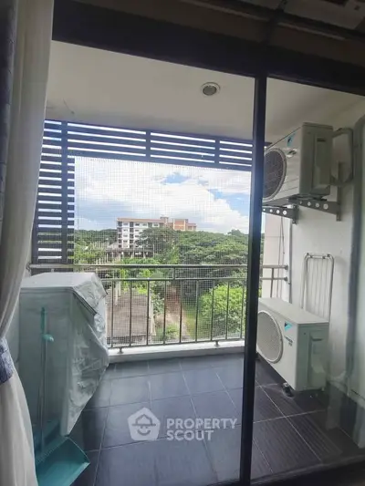Modern balcony with air conditioning units and scenic view of greenery and buildings.