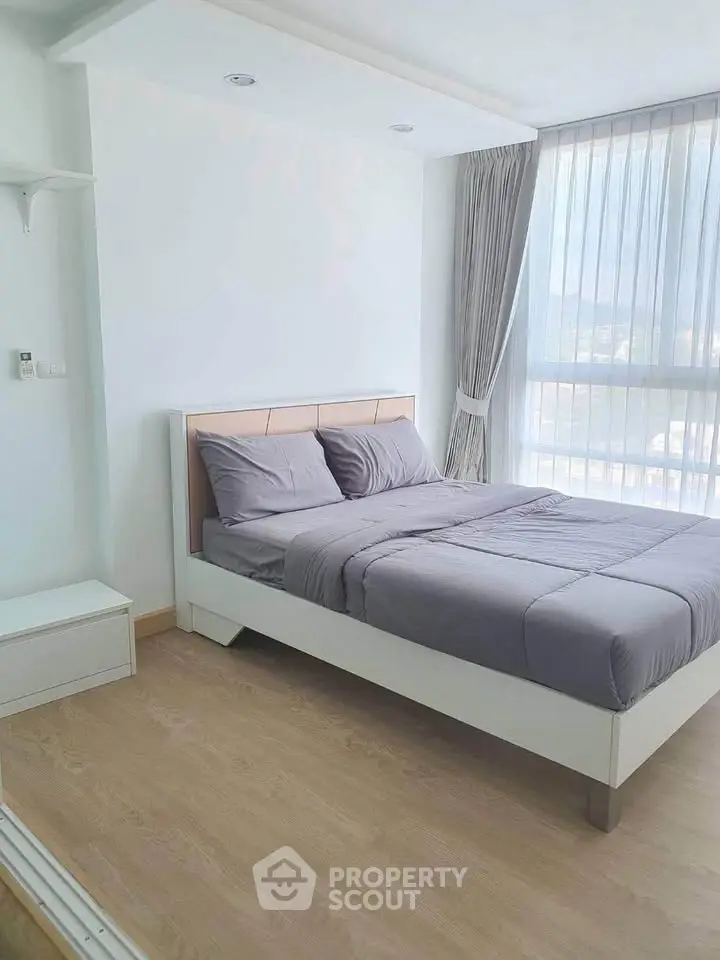 Modern bedroom with large window and stylish decor in a bright apartment.