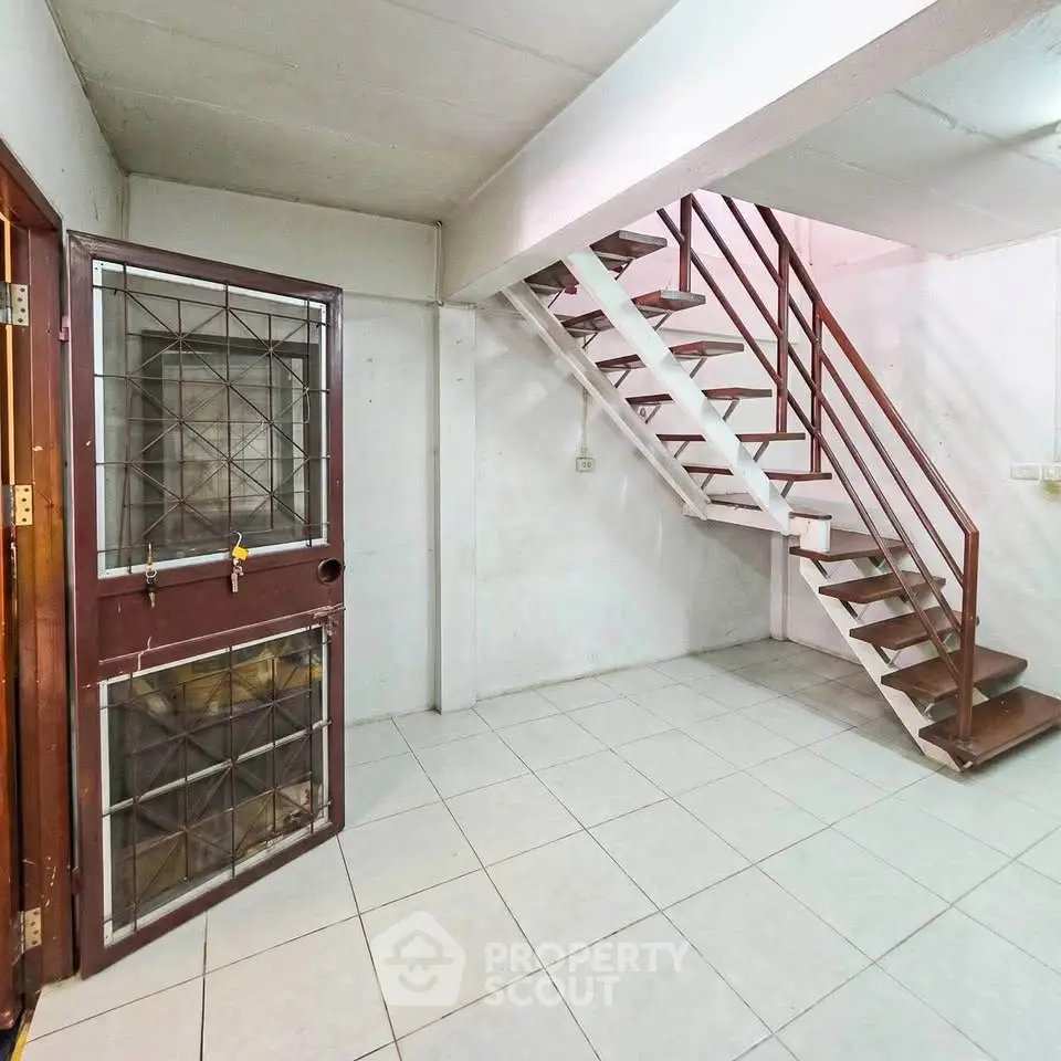 Spacious basement area with tiled flooring and metal staircase, ideal for storage or renovation.