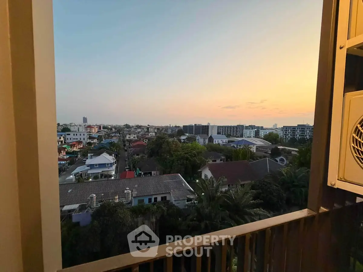 Stunning sunset view from a high-rise balcony overlooking a vibrant cityscape.