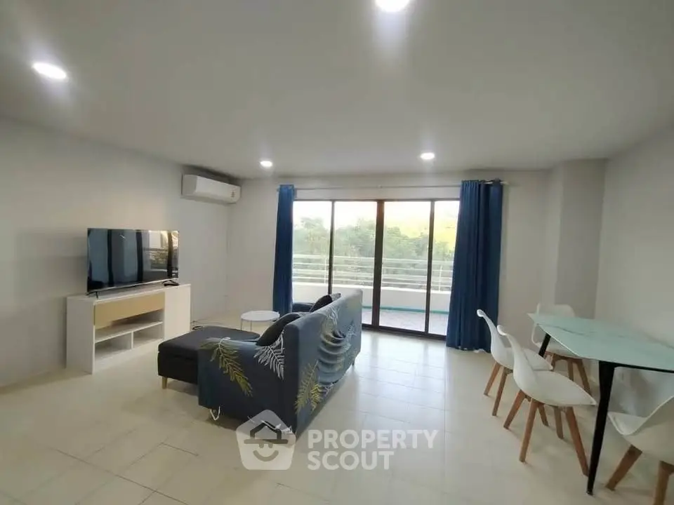 Spacious living room with modern decor and large balcony access.