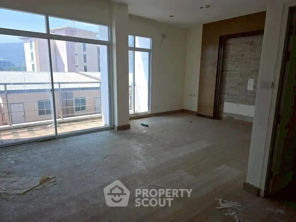 Spacious unfurnished room with large windows and balcony access, ideal for customization.