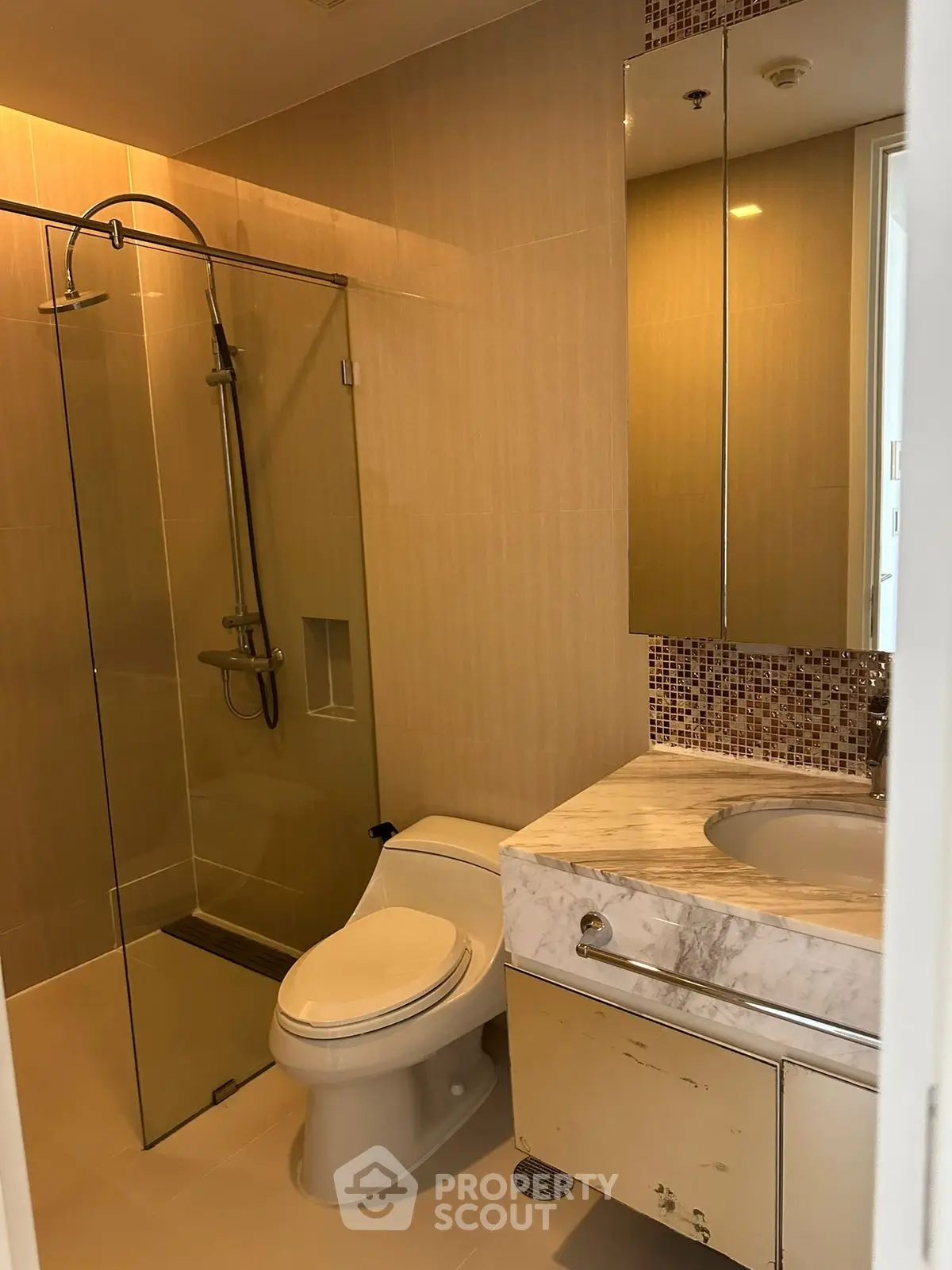 Modern bathroom with glass shower and marble sink in luxury apartment.
