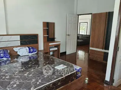 Spacious bedroom with modern furniture and polished wooden floors.