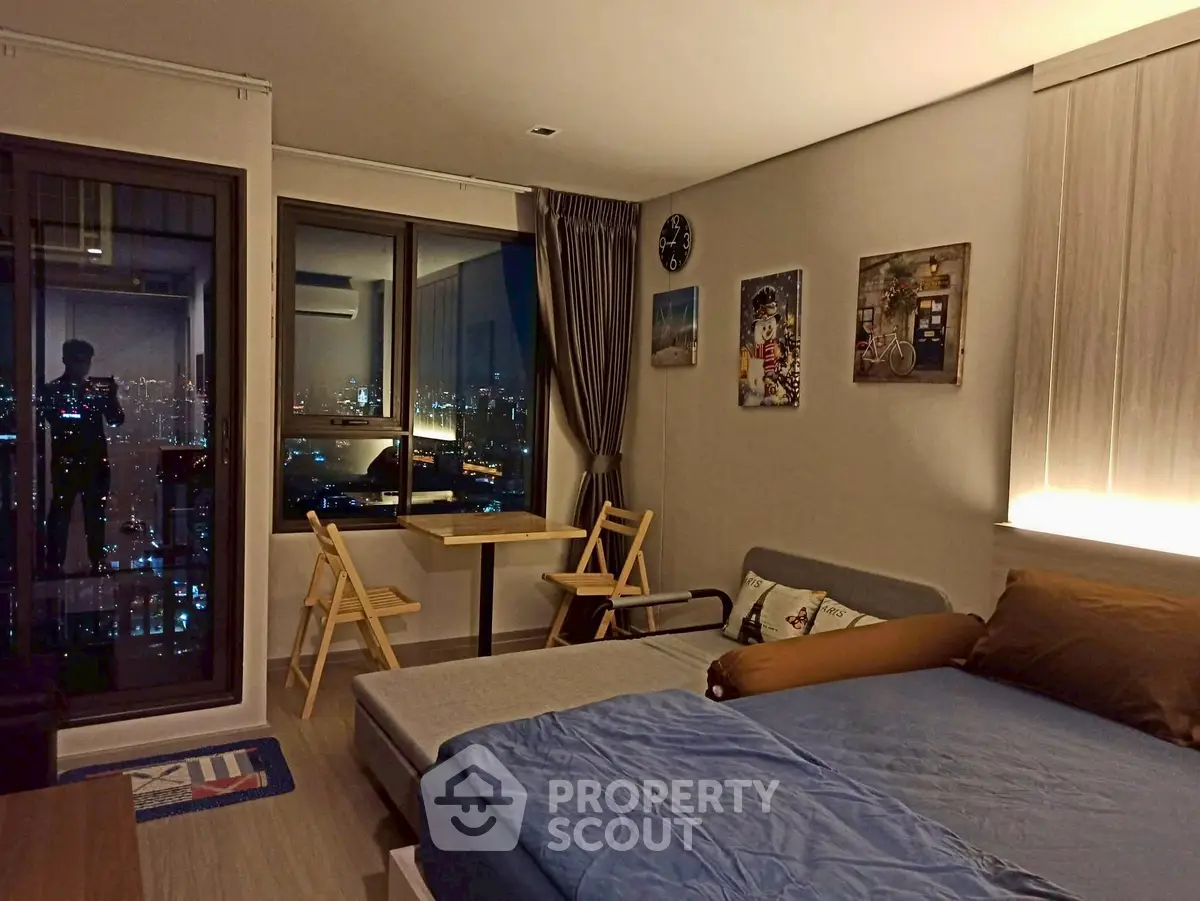 Modern studio apartment with city view, cozy furnishings, and ambient lighting.