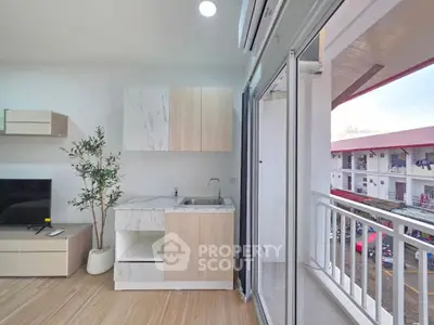Modern apartment with open kitchen and balcony view, featuring sleek cabinetry and natural light.