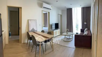 Modern living room with stylish furniture and natural light, featuring a cozy dining area and open layout.