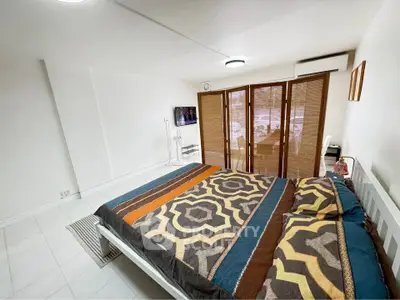 Spacious bedroom with modern decor and large windows for natural light.