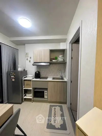 Modern compact kitchen with sleek cabinetry and appliances in a cozy apartment setting.