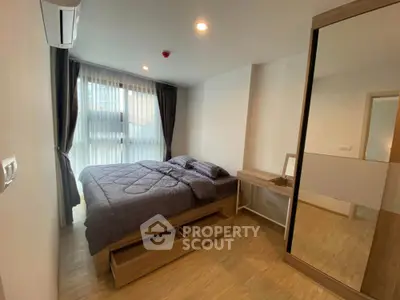 Modern bedroom with large window, wooden flooring, and sleek furniture in a stylish apartment.