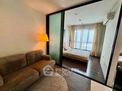 Modern apartment with cozy living room and stylish bedroom separated by glass partition.