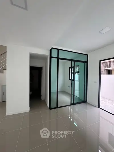 Modern interior with glass partition and sleek tile flooring in a bright, open space.