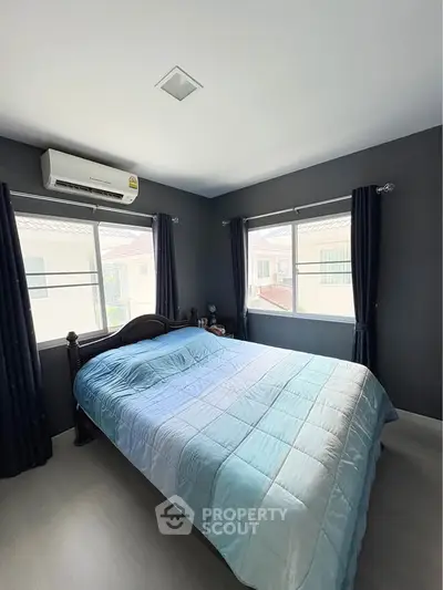 Cozy bedroom with large windows and modern air conditioning unit.