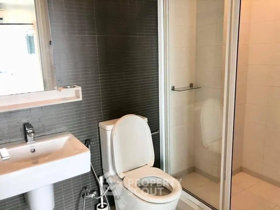 Modern bathroom with sleek design featuring a shower and contemporary fixtures.