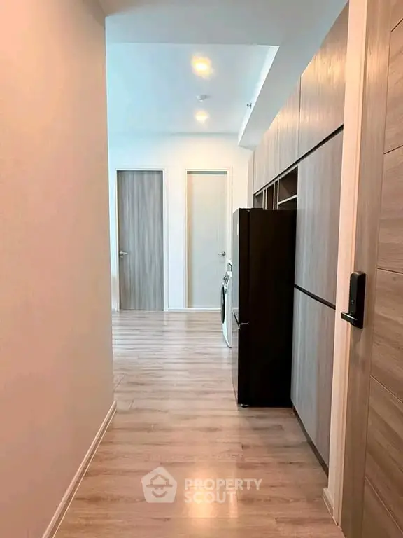 Modern hallway with sleek wooden flooring and built-in storage cabinets.