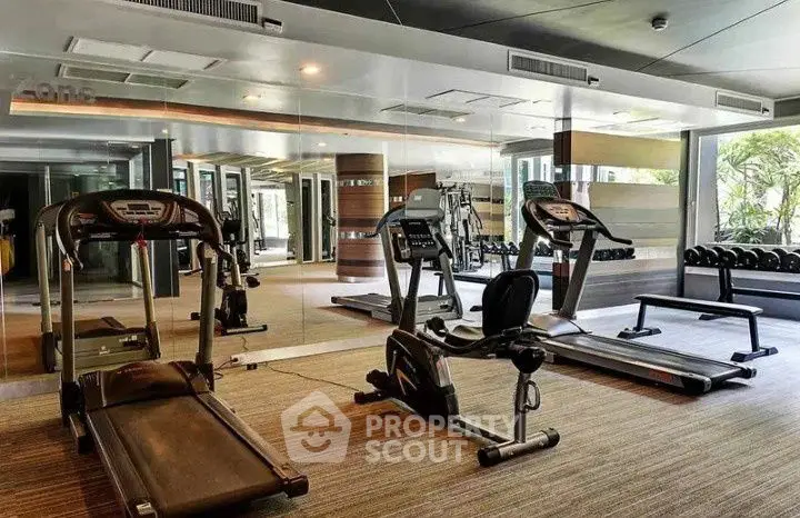 Modern gym with state-of-the-art equipment and mirrored walls in luxury apartment complex.
