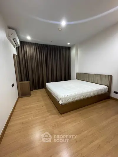 Spacious modern bedroom with wooden flooring and elegant curtains in a minimalist design.
