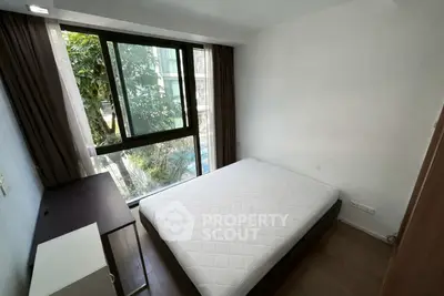 Cozy bedroom with large window overlooking lush greenery and pool view