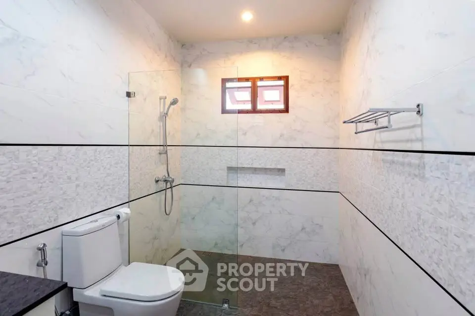 Modern bathroom with glass shower and marble walls