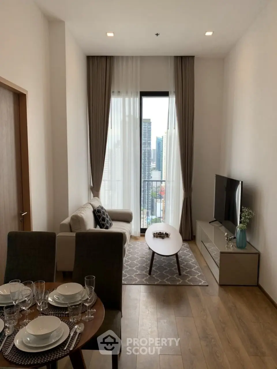 Modern living room with city view, elegant decor, and dining area in a high-rise apartment.