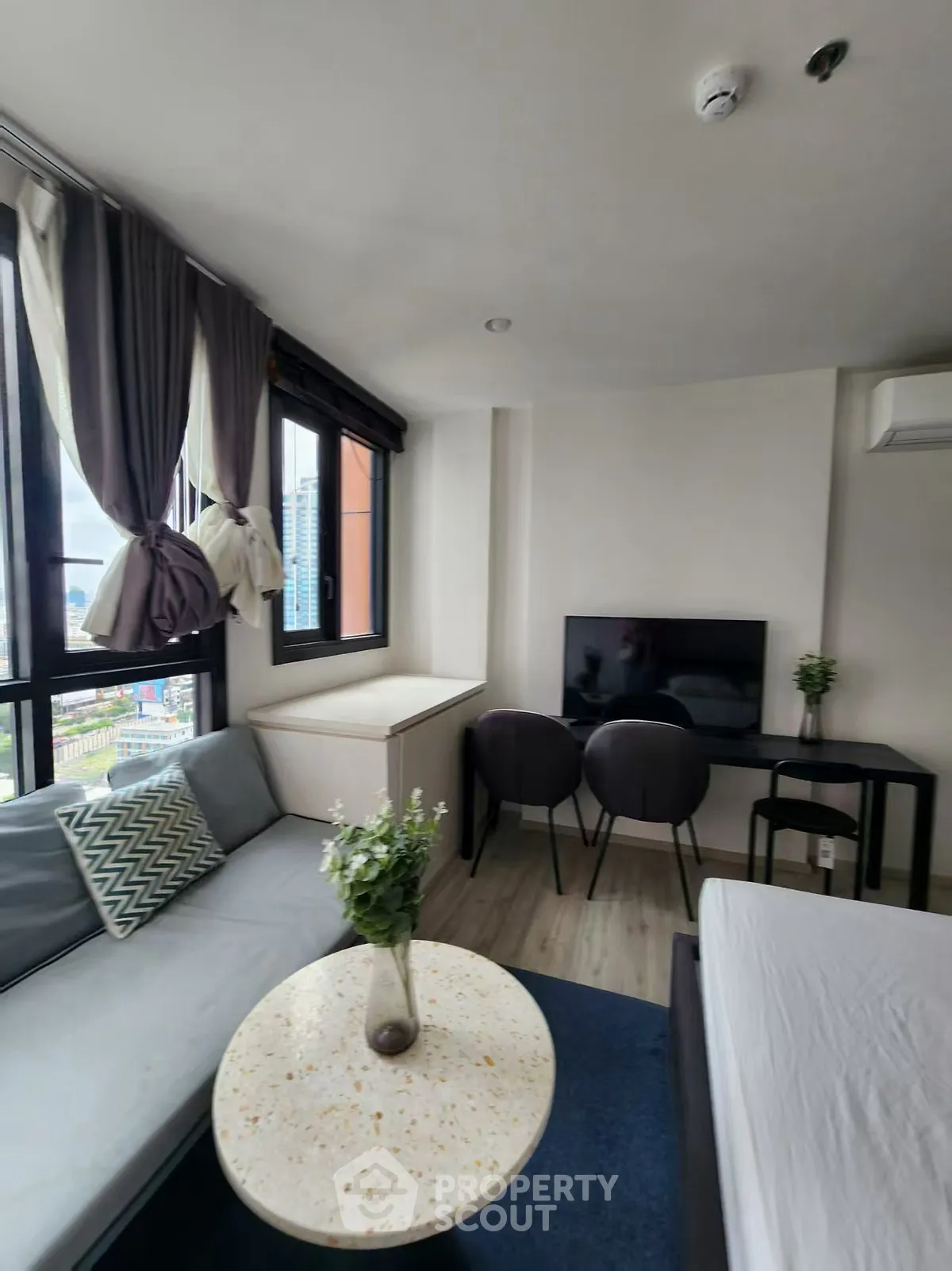 Modern living room with stylish decor and large windows offering city views.