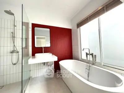 Modern bathroom with freestanding tub and red accent wall