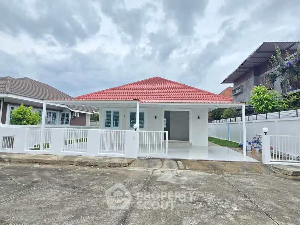 Charming single-story house with red roof and white fence, perfect for family living in a serene neighborhood.