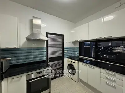Modern kitchen with sleek cabinetry, built-in oven, and washing machine.