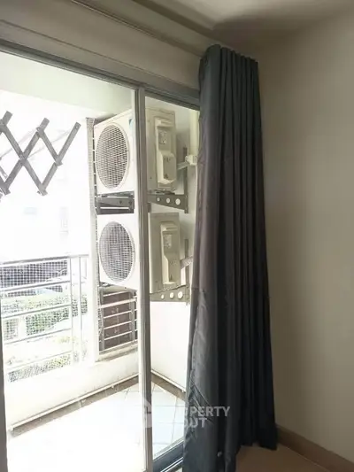Modern apartment balcony with air conditioning units and sliding glass door.