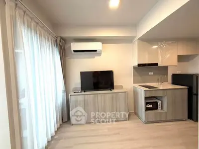 Modern living room with sleek kitchen, air conditioning, and natural light from large windows.