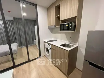 Modern compact kitchen with washing machine and microwave in stylish apartment